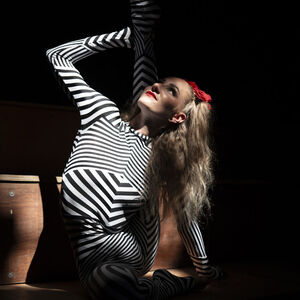 Een superlenig slangenmeisje steekt lachend een been recht omhoog achter haar hoofd langs.