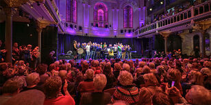 Een volle zaal in Paradiso geniet van een groot koor op het podium.