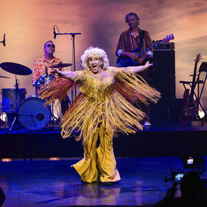Karin Bloemen in een goud pak met franjes. Ze draait rond waardoor de franjes alle kanten op zwieren. 