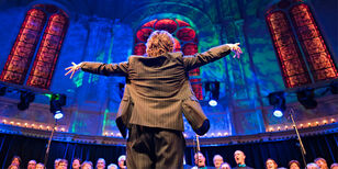 Een uitbundig dirigerende dirigent voor een koor in Paradiso.