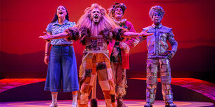 Dorothy, de vogelverschrikker en de blikken man zingen samen met de Leeuw.