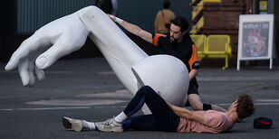 Een reusachtige gebeeldhouwde witte arm. Ernaast 2 dansers.