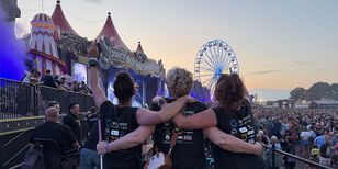 Voor het grote hoofdpodium van de Zwarte Cross genieten drie vriendinnen gearmd van de muziek. Een vrouw heeft een taststok.