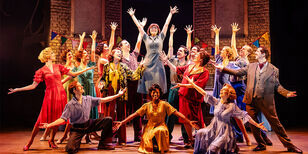 Alle acteurs van Foxtrot in een vrolijke showpose met hun handen hoog in de lucht.