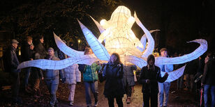 Een groep mensen draagt een grote van rijstpapier gemaakte lichtgevende octopus tijdens de Sint Maartenparade.