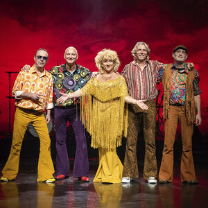 Karin Bloemen omringt door de drie mannen van haar band. Ze dragen allemaal jaren 70 kleding. 
