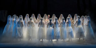 24 met witte tule gesluierde danseressen staan in een grote kring om Giselle heen.