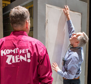 slechtziende tast een deur in het decor van musical De Marathon