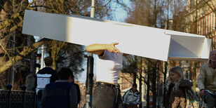 Een vrouw loopt met een witte Ikea Billy boekenkast over straat. Haar hoofd verdwijnt tussen de planken.