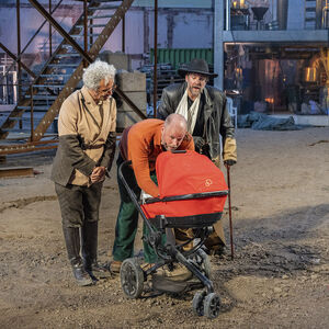 Drie mannen staan om een kinderwagen heen. 