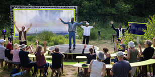Vier acteurs nemen applaus in ontvangst op een open plek in het bos.