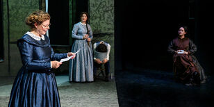 Een van de zussen leest een brief voor. Twee andere zussen luisteren aandachtig op de achtergrond mee. 