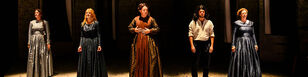 Vijf personages staan naast elkaar op het toneel. De vier vrouwen dragen Victoriaanse lange jurken met een strak bovenlijfje.